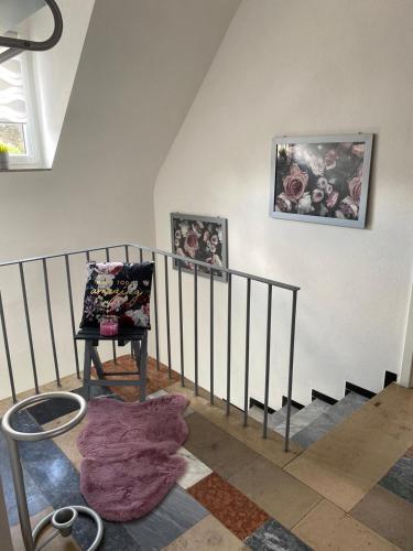 a room with a staircase with a chair and some pictures at Erica Ferienwohnung auf dem Traumpfad in Ettringen