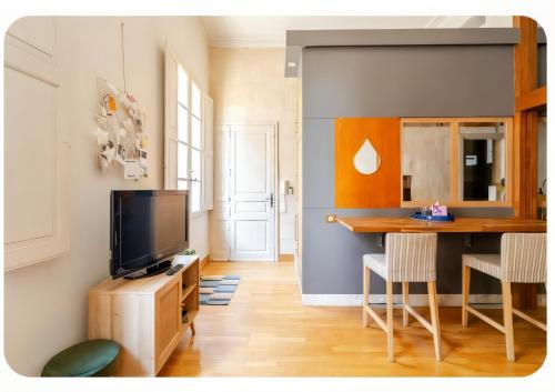 a living room with a television and a table at L' Appart du Centre Historique Charme et confort in Arles
