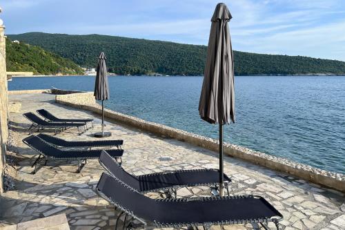 a group of chairs and umbrellas next to a lake at Sea Salt Apartment in Kruče