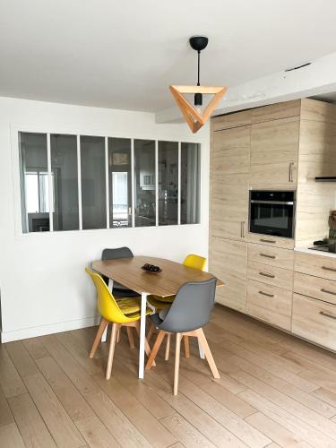 a dining room with a wooden table and yellow chairs at Charme et confort à 5 min du RER in Saint-Germain-en-Laye