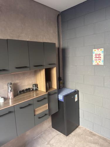 a kitchen with gray cabinets and a small refrigerator at Loft Roots in Joanópolis