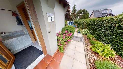 a walkway leading to a house with pink flowers at Fewo Wattfischer II in Cuxhaven