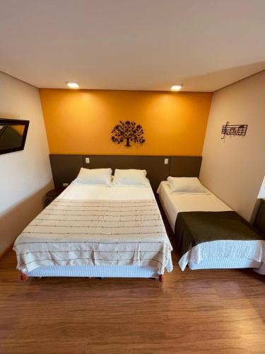 two beds in a room with yellow walls at Pousada Cantinho da Serra in Campos do Jordão