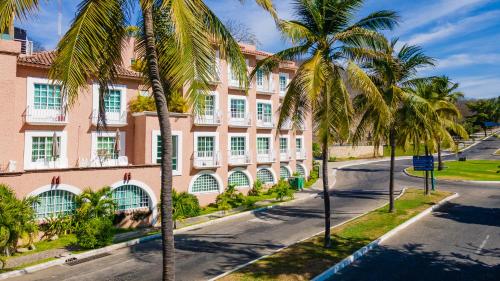 an empty street in front of a pink building with palm trees at Hotel Castillo Huatulco & Beach Club in Santa Cruz Huatulco