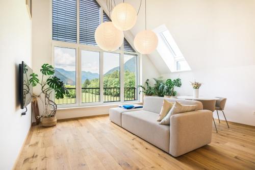 a living room with a couch and a table and windows at Nomad 27 in Bovec