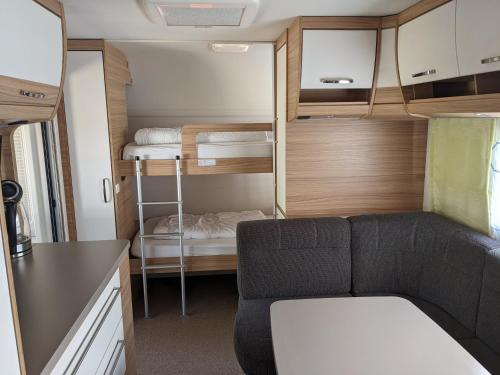 een kleine caravan met een bank en stapelbedden bij Luxuswohnwagen Butterfisch am Kransburger See 420 in Kransburg