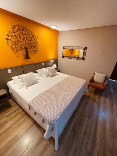 a bedroom with a large bed with a yellow wall at Pousada Cantinho da Serra in Campos do Jordão