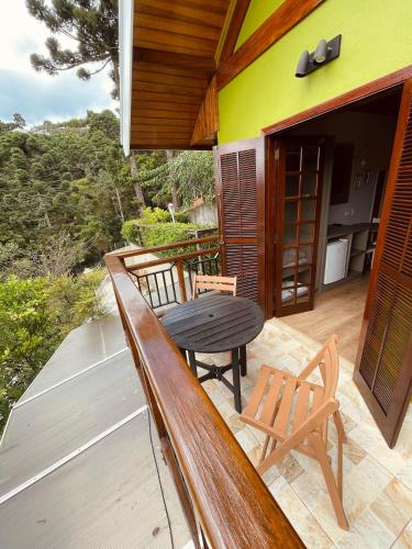 a wooden bench on a deck with a table and chairs at Pousada Cantinho da Serra in Campos do Jordão