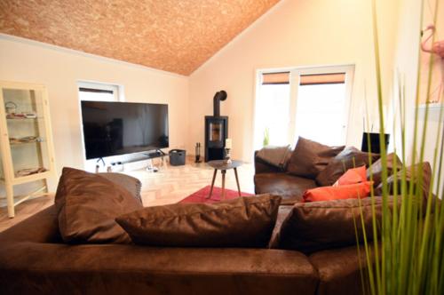 Una sala de estar con un sofá marrón y un televisor de pantalla plana. en Ferienwohnung Nr 4, en Wunstorf