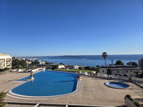 une piscine bleue avec l'océan en arrière-plan dans l'établissement Sisley 1061 - F2 Terrasse avec vue mer, à Cannes