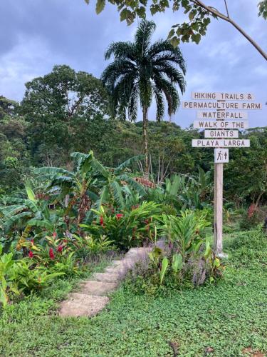 a sign in front of a garden with a palm tree at La Tierra Del Encanto in Bocas del Toro