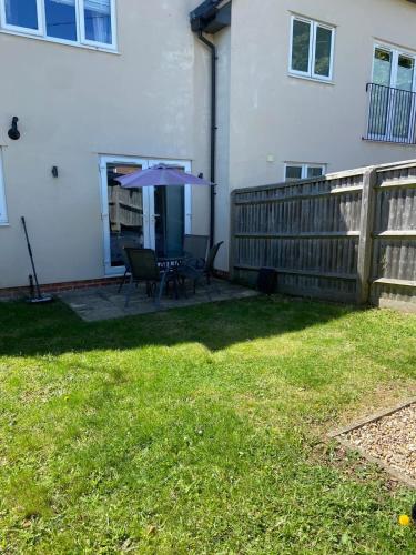 a patio with a table and an umbrella in a yard at 2 Bed Garden Apartment in Yarnton