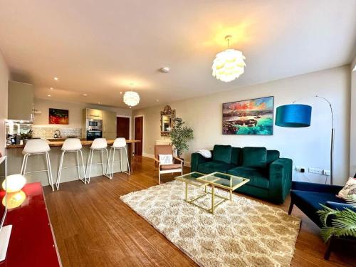 a living room with a green couch and a kitchen at 2 Bed Garden Apartment in Yarnton