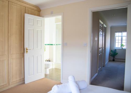 a bathroom with a door leading to a bathroom with a toilet at 4x Bed Elegant Home with Parking in Ely