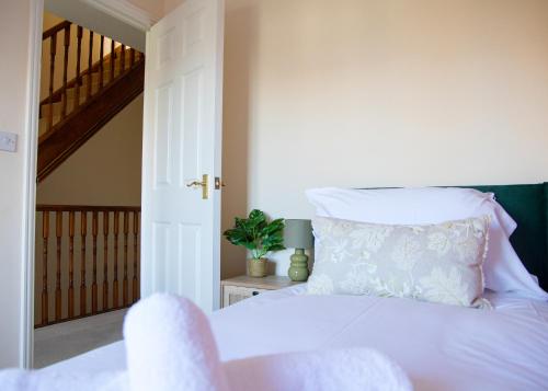 a bedroom with a white bed and a staircase at 4x Bed Elegant Home with Parking in Ely