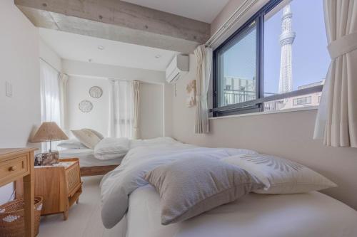 a white bedroom with two beds and a window at Cloud Nine Apartment Sky Tree in Tokyo