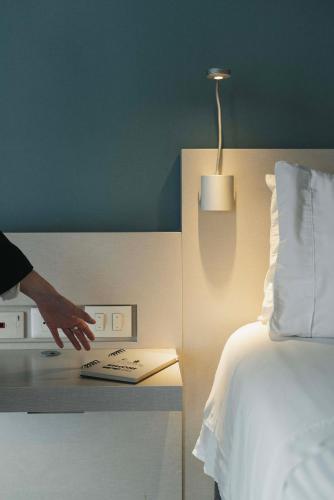 a person reaching for a book on a table next to a bed at Hotel Black Tower Premium in Bogotá