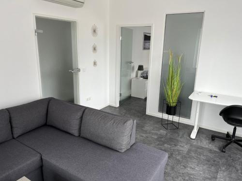 a living room with a gray couch and a desk at Ferienwohnung bei Jennifer in Gütersloh