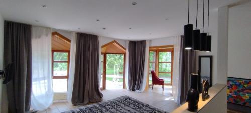 a living room with windows and a red chair at Fichtennest in Bingerbrück