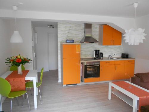 a kitchen with orange cabinets and a table and a dining room at Ferienwohnung Haus Glückauf in Kölpinsee