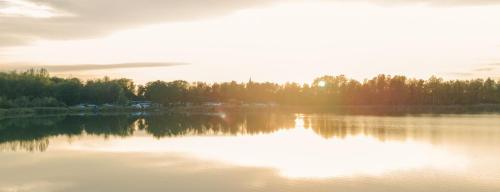 a lake with the sun reflecting on the water at Ferienhaus 4 Personen FH6 in Hindenberg