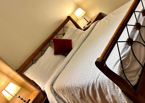 a bedroom with a bed with white sheets and a red pillow at شقة فندقية علي النيل للعائلات بالقاهرة in Cairo