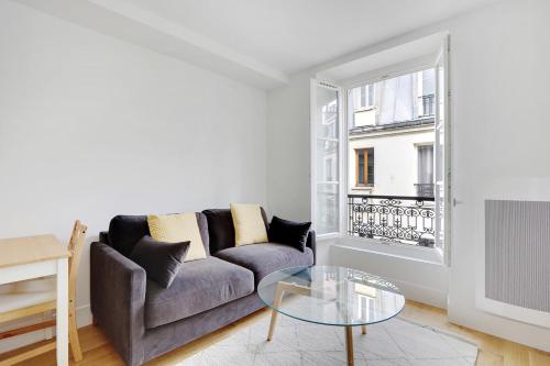 un salon avec un canapé et une table en verre dans l'établissement Flexliving - One-bedroom apartment - Leriche, à Paris