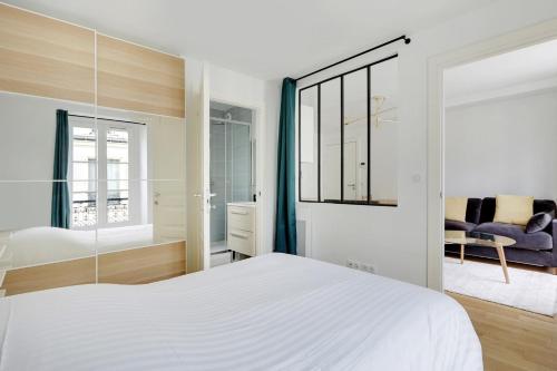 une chambre avec un lit blanc et un miroir dans l'établissement Flexliving - One-bedroom apartment - Leriche, à Paris