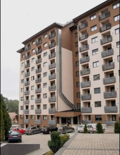 a large building with cars parked in a parking lot at Vila Pekovic Central-Apartman PAMA in Zlatibor