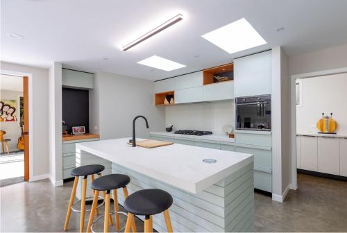 a kitchen with white cabinets and bar stools at 5 o'clock Somewhere in Masterton