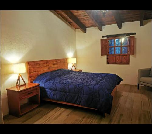 a bedroom with a bed and a table and a window at Cabañas Tapalpa la laja in Los Espinos