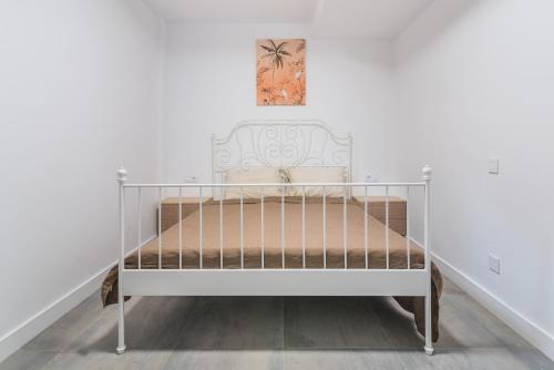 Una cama blanca en una habitación con una foto en la pared en Playa de las Mujeres, en San Bartolomé