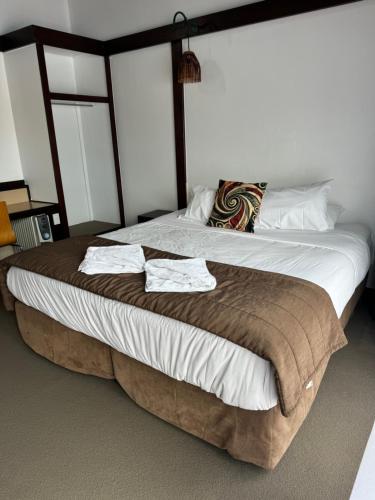 a bedroom with a large bed with two towels on it at Tokaanu Hotel in Tokaanu