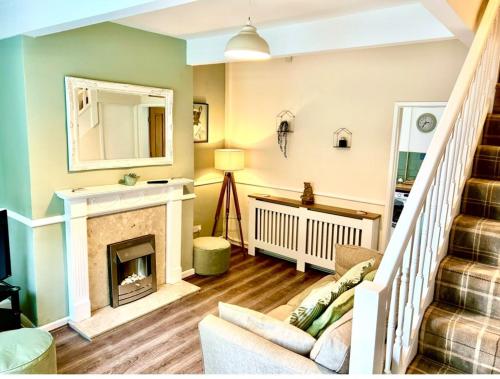 a living room with a fireplace and a staircase at The Little Green Cosy Cottage in Bury
