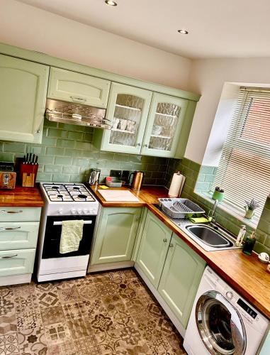 a kitchen with green cabinets and a washer at The Little Green Cosy Cottage in Bury