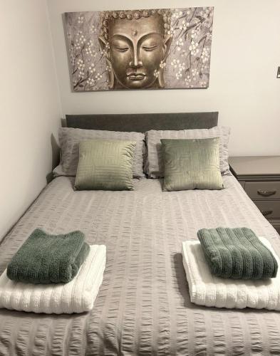a bed with two pillows and a large headboard at The Little Green Cosy Cottage in Bury