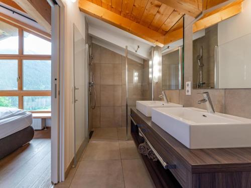a bathroom with two sinks and a shower at Chalet Huski Viehhofen in Saalbach Hinterglemm