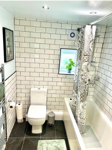 a bathroom with a toilet and a shower curtain at The Little Green Cosy Cottage in Bury