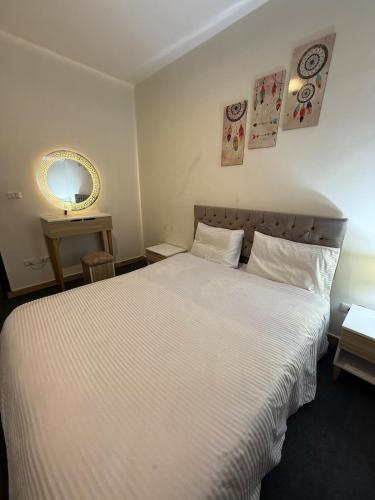 a bedroom with a large white bed and a mirror at Elegant apartment with garden in Sheikh Zayed