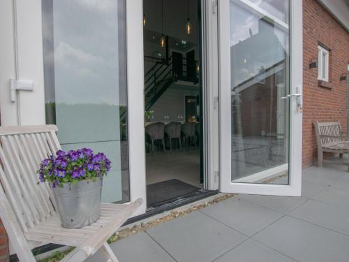 a porch with a bench with a bucket of purple flowers at Jonkershof in Zevenhuizen