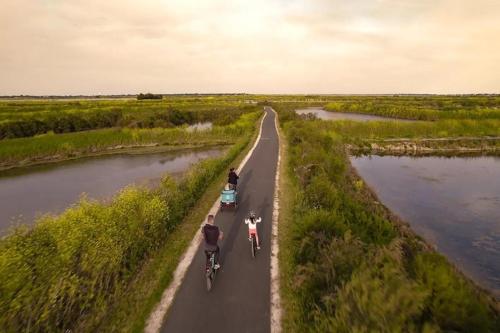 two people riding bikes down a road next to a river at Apartment in Ars-en-Ré near Bird Sanctuary in Ars-en-Ré