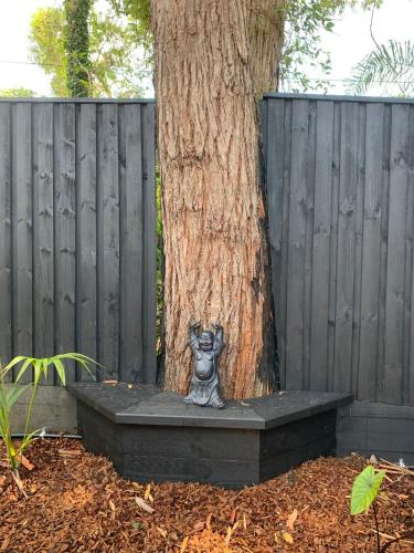 a statue of a dog sitting next to a tree at Jezabel's Retreat Jervis Bay in Vincentia