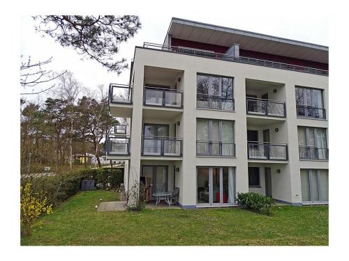 a large white building with balconies and a yard at Beach Dune Comfortable holiday residence in Juliusruh
