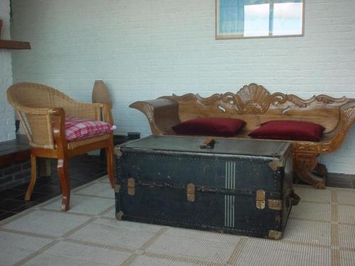 a bedroom with a bed with a trunk and a chair at Pacific Ocean View Comfortable Holiday Residence in Bergen aan Zee