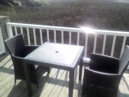a table and two chairs sitting on a deck at Pacific Ocean View Comfortable Holiday Residence in Bergen aan Zee