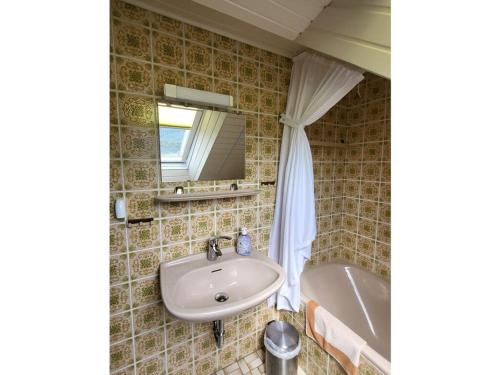 a bathroom with a sink and a tub and a mirror at Pension Sonnenberg Comfortable holiday residence in Silz