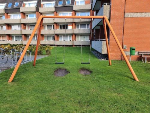 an orange swing set in the grass in front of a building at Holiday Apartment Holly Comfortable holiday residence in Borkum