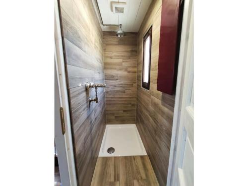 a small bathroom with a shower with wooden walls at Filmschip "Erbse" - buitengewoon woonboot op het land in Wiesentheid