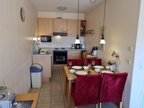 a kitchen with a dining table and red chairs at Möwennest 2 Apartment 35 Comfortable holiday residence in Borkum