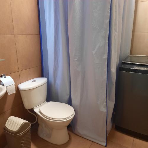 a bathroom with a toilet and a shower curtain at Apartamento moderno y comodo in Cochabamba